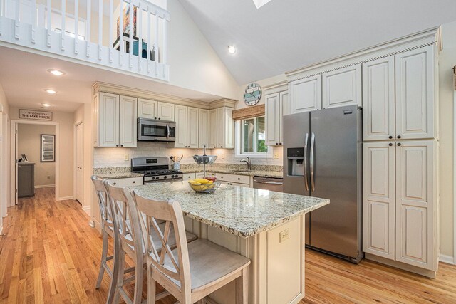 12215 Dunes Rd, Sawyer, MI 49125 - kitchen with stainless steel appliances, a sink, light wood finished floors, light stone counters, and high vaulted ceiling