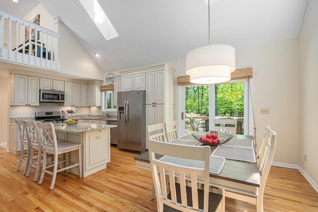 12215 Dunes Rd, Sawyer, MI 49125 - kitchen featuring stainless steel appliances, a skylight, a kitchen island, light wood-type flooring, and backsplash