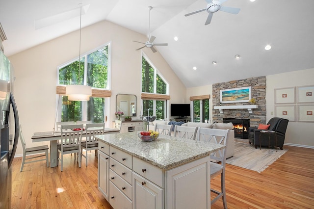 12215 Dunes Rd, Sawyer, MI 49125 - kitchen featuring a breakfast bar, high vaulted ceiling, light wood-type flooring, a fireplace, and ceiling fan