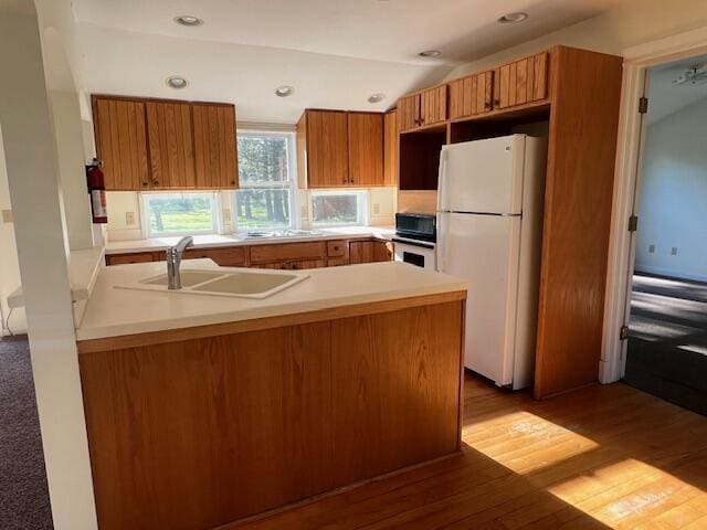52 N Webster St, White Cloud, MI 49349 - kitchen with freestanding refrigerator, a sink, brown cabinets, and lofted ceiling