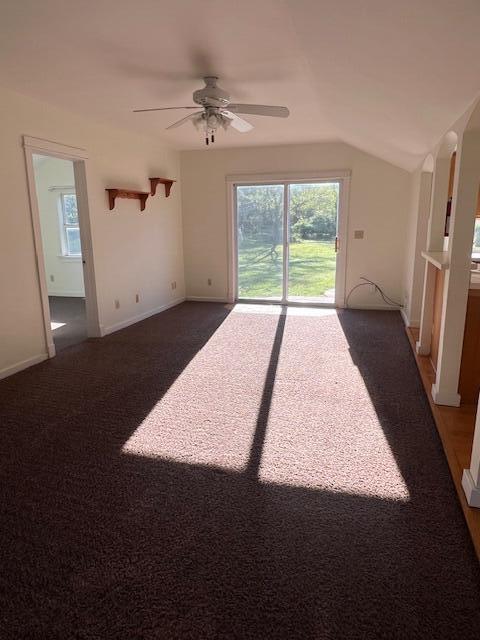 52 N Webster St, White Cloud, MI 49349 - empty room featuring a ceiling fan, dark carpet, lofted ceiling, baseboards, and arched walkways