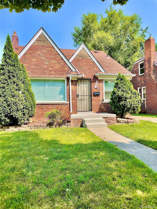 18694 Beland St, Detroit, MI 48234 - view of front of house featuring brick siding, a front lawn, and a chimney