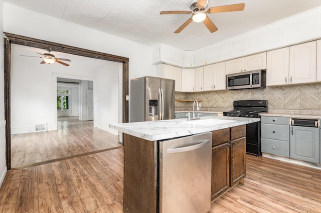 1508 Mckinley St, Bay City, MI 48708 - kitchen with stainless steel appliances, a ceiling fan, a sink, light wood-type flooring, and backsplash