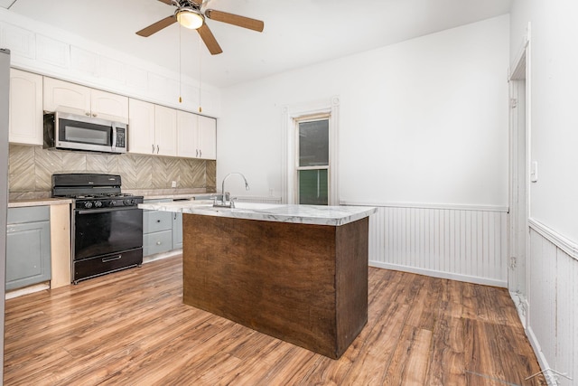 1508 Mckinley St, Bay City, MI 48708 - kitchen with stainless steel microwave, black gas stove, light countertops, ceiling fan, and wood finished floors