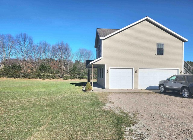 6039 W Morris Lake Rd, Mears, MI 49436 - view of property exterior with an attached garage, dirt driveway, and a yard