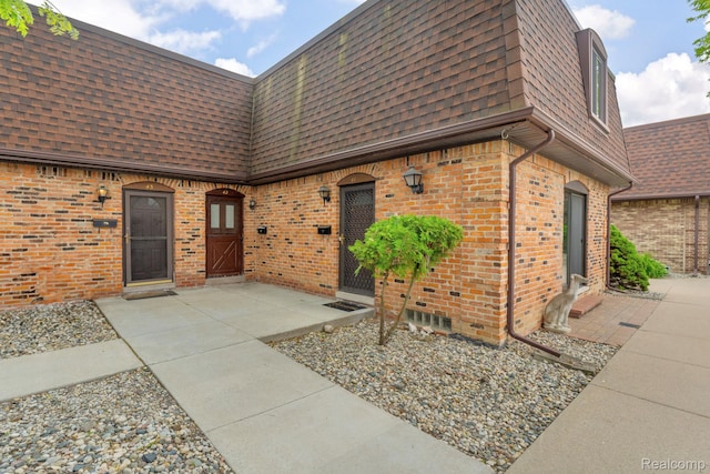 5025 Crooks Rd Unit 42, Royal Oak, MI 48073 - doorway to property featuring mansard roof, roof with shingles, and brick siding
