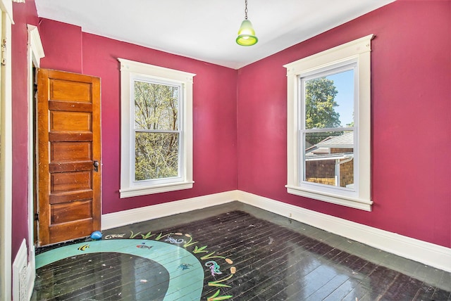 115 N Emily, Ludington, MI 49431 - unfurnished room with baseboards, plenty of natural light, and hardwood / wood-style floors