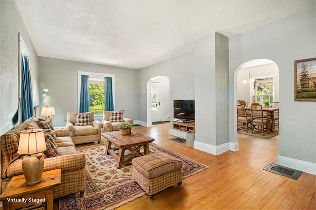 115 N Emily, Ludington, MI 49431 - living room featuring arched walkways, light wood-style flooring, and baseboards