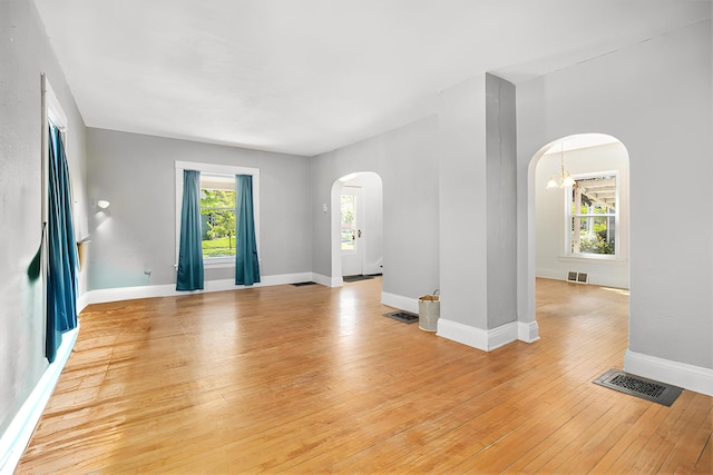 115 N Emily, Ludington, MI 49431 - unfurnished room with arched walkways, plenty of natural light, light wood-style floors, and baseboards