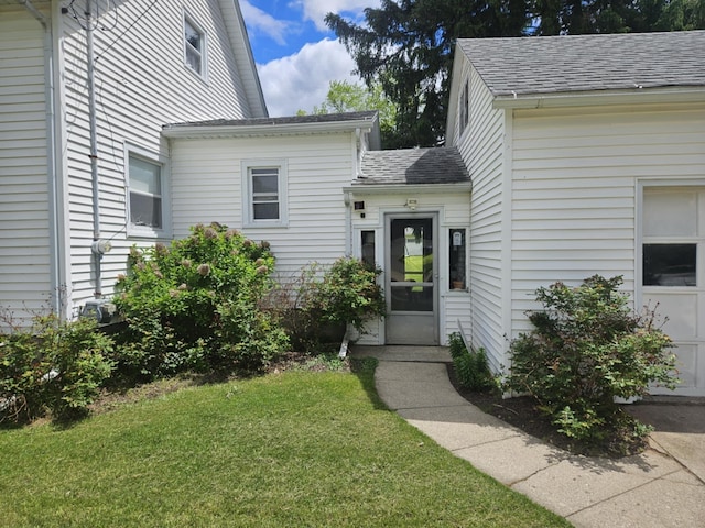 527 Jones St, Grand Ledge, MI 48837 - view of exterior entry with roof with shingles and a yard