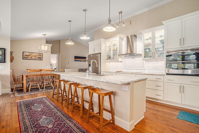 7431 W Buchanan Rd, Shelby, MI 49455 - kitchen with wall chimney exhaust hood, a sink, backsplash, a kitchen bar, and wood finished floors