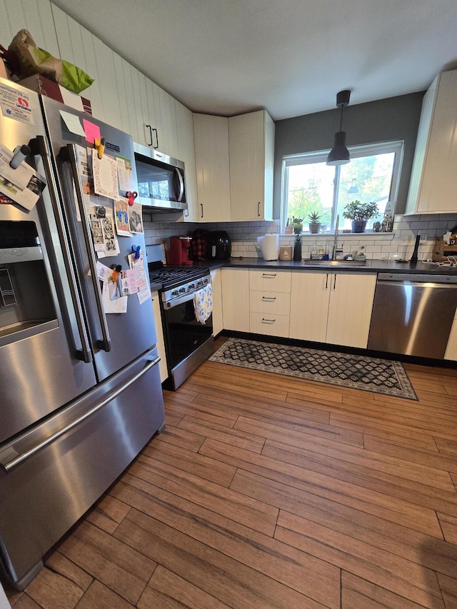 5966 Engleman Ave, Warren, MI 48091 - kitchen with stainless steel appliances, a sink, dark countertops, dark wood-type flooring, and backsplash