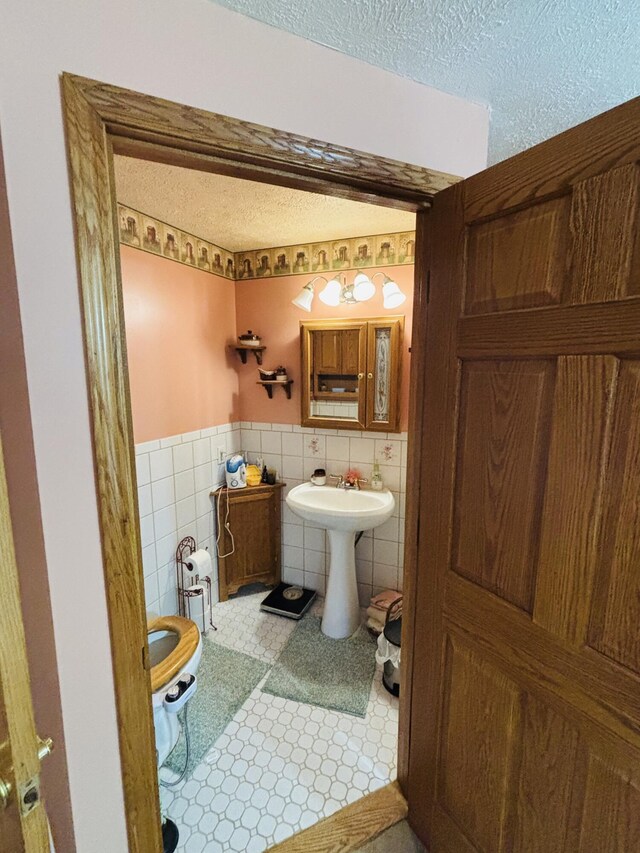 4375 W Haskell Lake Rd, Harrison, MI 48625 - half bath featuring tile walls, a textured ceiling, and wainscoting