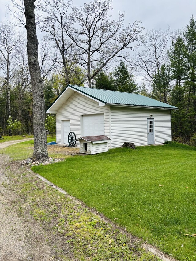 4375 W Haskell Lake Rd, Harrison, MI 48625 - view of side of home with an outbuilding, a yard, a metal roof, and a garage