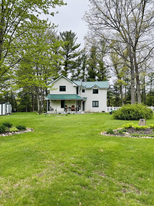 4375 W Haskell Lake Rd, Harrison, MI 48625 - rear view of house with a porch, a yard, a storage unit, and a metal roof