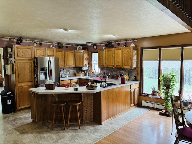 4375 W Haskell Lake Rd, Harrison, MI 48625 - kitchen featuring stainless steel fridge with ice dispenser, a textured ceiling, light countertops, brown cabinets, and a peninsula