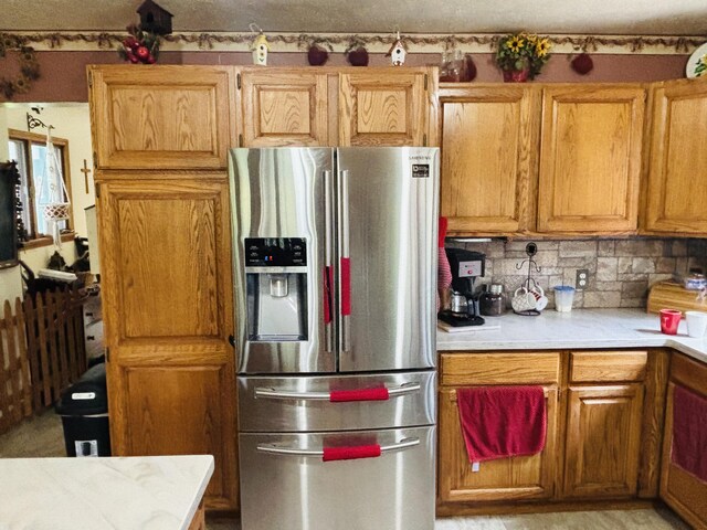 4375 W Haskell Lake Rd, Harrison, MI 48625 - kitchen with stainless steel fridge, light countertops, decorative backsplash, and brown cabinetry