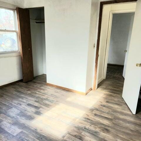 5678 Leona Ave, Muskegon, MI 49442 - unfurnished bedroom featuring wood finished floors, baseboards, and a closet