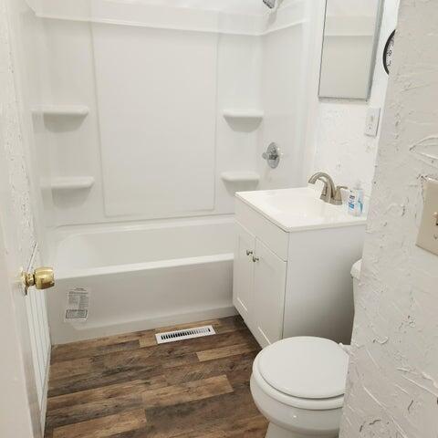 5678 Leona Ave, Muskegon, MI 49442 - bathroom featuring vanity, toilet, wood finished floors, and bathing tub / shower combination