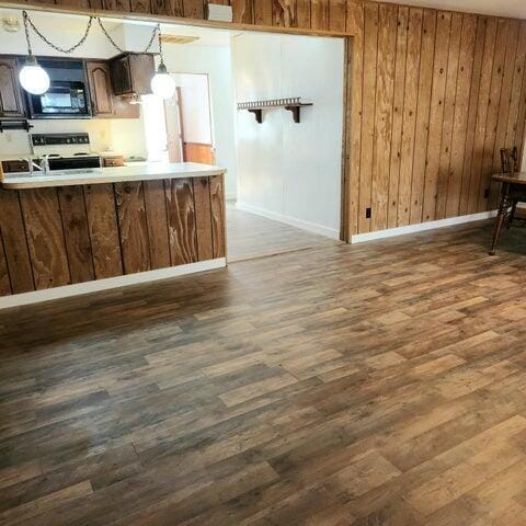 5678 Leona Ave, Muskegon, MI 49442 - kitchen featuring black microwave, dark wood-type flooring, electric stove, baseboards, and wood walls