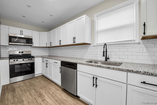 14850 Ilene St, Detroit, MI 48238 - kitchen featuring appliances with stainless steel finishes, a sink, white cabinets, and decorative backsplash