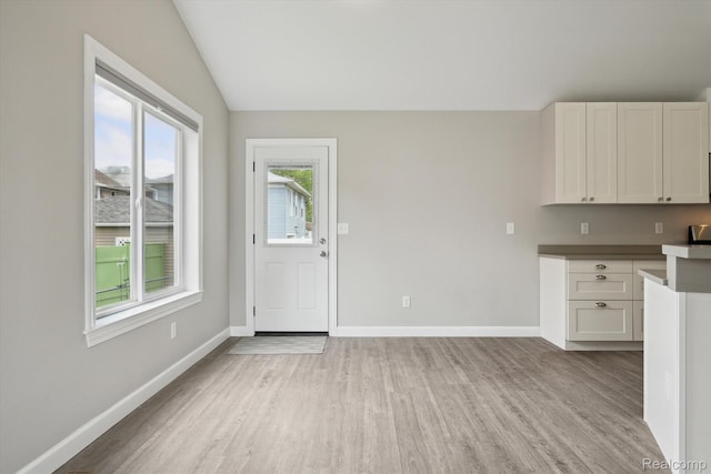 1759 2nd St, Taylor, MI 48192 - kitchen featuring light wood-style floors, baseboards, lofted ceiling, and white cabinets