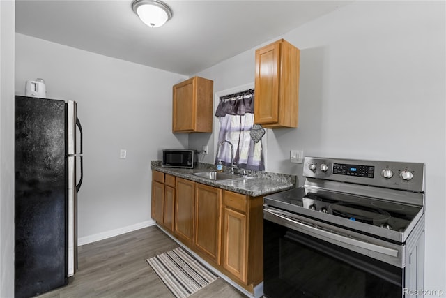 18625 Carrie St, Detroit, MI 48234 - kitchen with stainless steel appliances, a sink, wood finished floors, dark countertops, and brown cabinetry