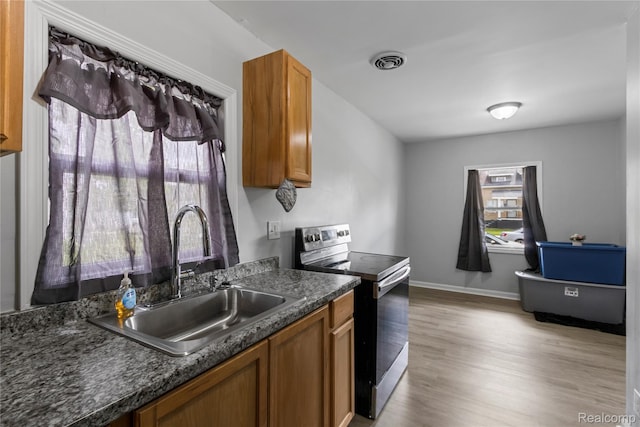 18625 Carrie St, Detroit, MI 48234 - kitchen with stainless steel electric stove, a sink, dark countertops, light wood-style floors, and brown cabinets
