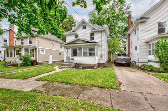 1118 Burr St, Jackson, MI 49201 - view of front of property featuring entry steps, a front lawn, concrete driveway, and a sunroom