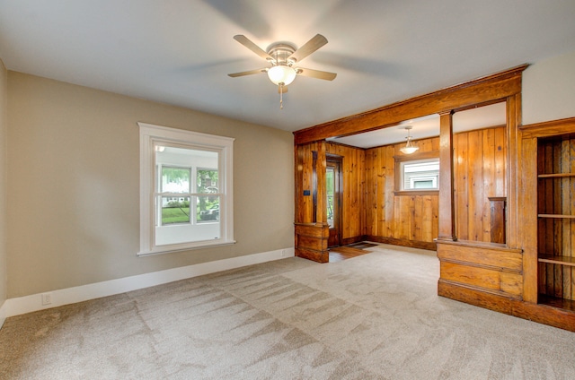 1118 Burr St, Jackson, MI 49201 - carpeted empty room featuring baseboards, wood walls, a ceiling fan, and beamed ceiling