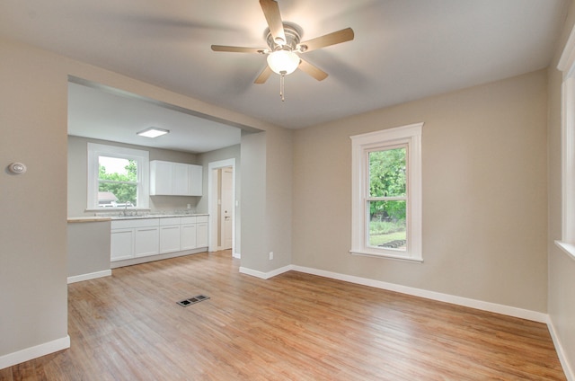 1118 Burr St, Jackson, MI 49201 - unfurnished living room with a ceiling fan, a sink, baseboards, and light wood-type flooring