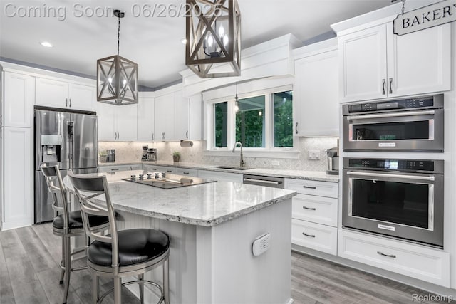 800 Greystone Dr, Chelsea, MI 48118 - kitchen with appliances with stainless steel finishes, a center island, white cabinets, recessed lighting, and light wood-type flooring