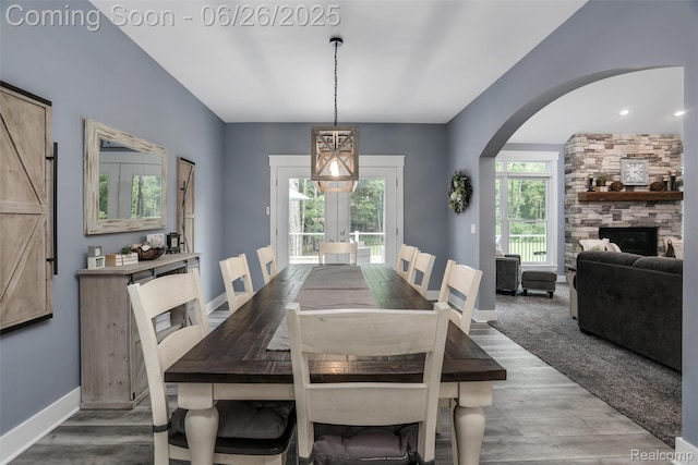 800 Greystone Dr, Chelsea, MI 48118 - dining space featuring wood finished floors, arched walkways, a stone fireplace, and french doors