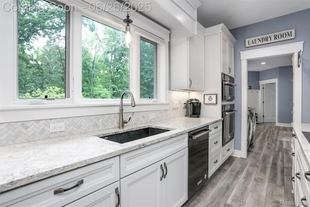 800 Greystone Dr, Chelsea, MI 48118 - kitchen featuring washing machine and clothes dryer, stainless steel appliances, backsplash, white cabinets, and light stone counters