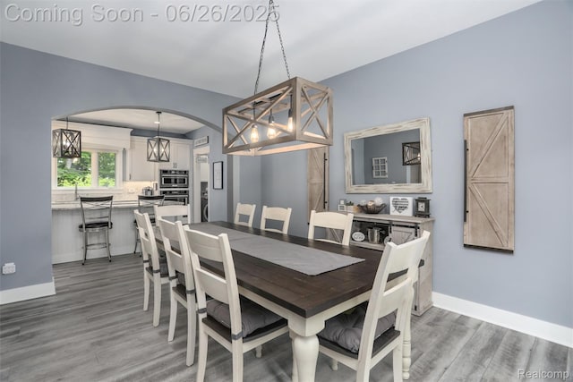800 Greystone Dr, Chelsea, MI 48118 - dining room with arched walkways, light wood-style floors, and a chandelier