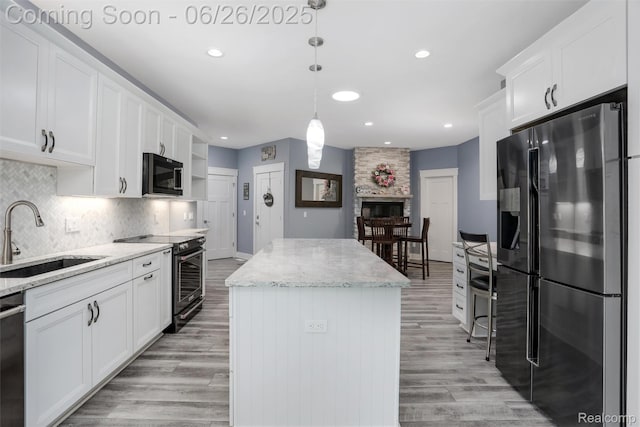 800 Greystone Dr, Chelsea, MI 48118 - kitchen with stainless steel appliances, a center island, white cabinetry, light wood-style flooring, and recessed lighting