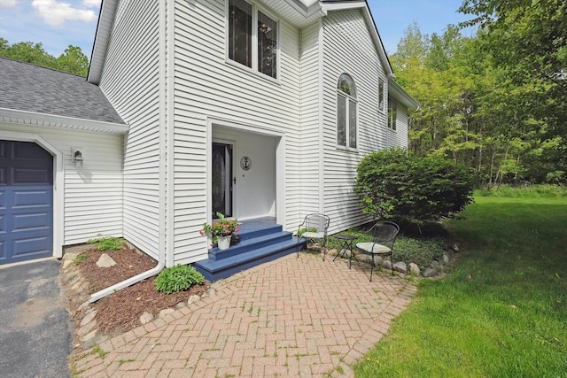 16350 Whitaker Rd, Linden, MI 48451 - view of exterior entry with a lawn, roof with shingles, and a garage
