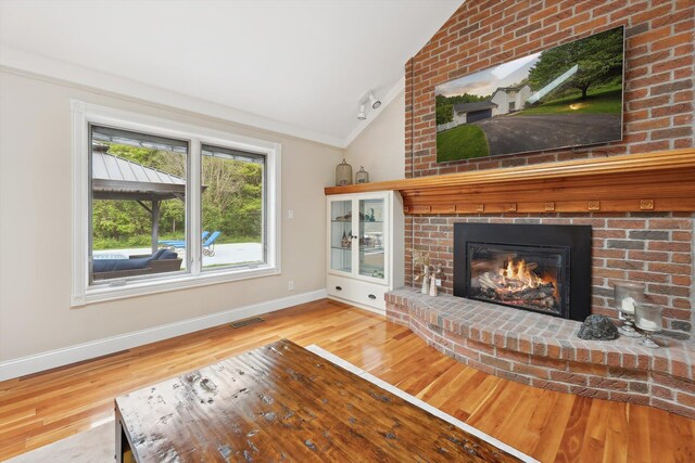 16350 Whitaker Rd, Linden, MI 48451 - unfurnished living room featuring vaulted ceiling, wood finished floors, a brick fireplace, and baseboards