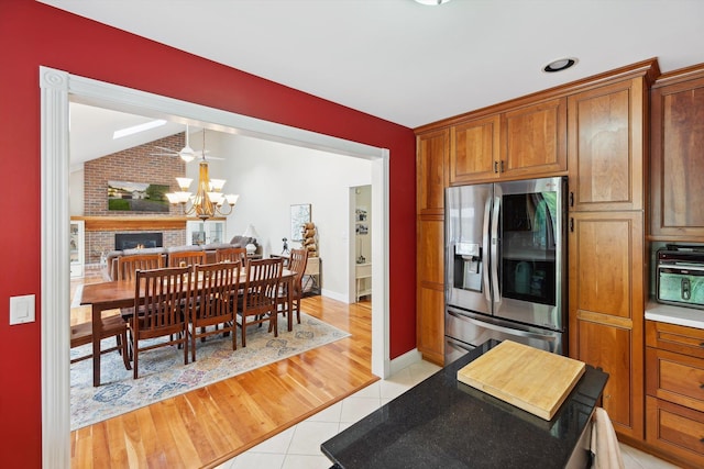 16350 Whitaker Rd, Linden, MI 48451 - kitchen with stainless steel fridge with ice dispenser, a chandelier, light tile patterned floors, brown cabinets, and vaulted ceiling