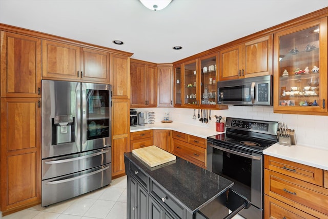 16350 Whitaker Rd, Linden, MI 48451 - kitchen with stainless steel appliances, brown cabinets, backsplash, light tile patterned flooring, and glass insert cabinets