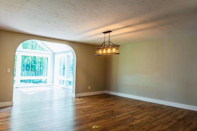 11775 Crystal Ridge Dr NE, Sparta, MI 49345 - empty room with baseboards, dark wood-style flooring, arched walkways, and a textured ceiling