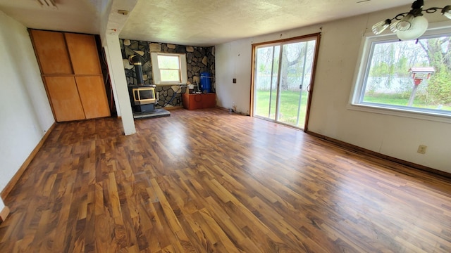 599 Ruby Rd, Sheridan, MI 48884 - unfurnished living room featuring a wood stove, wood finished floors, a textured ceiling, and baseboards