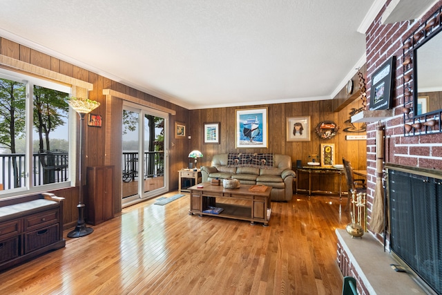 11676 Bradley Dr, Jerome, MI 49249 - living room featuring plenty of natural light, wood walls, hardwood / wood-style floors, crown molding, and a brick fireplace