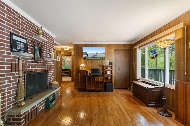 11676 Bradley Dr, Jerome, MI 49249 - living area featuring wood walls, hardwood / wood-style floors, a brick fireplace, and crown molding