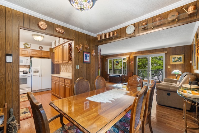 11676 Bradley Dr, Jerome, MI 49249 - dining space with wooden walls, a textured ceiling, and light wood finished floors