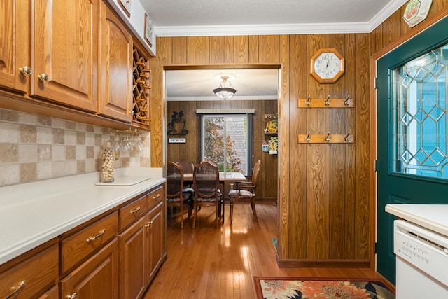 11676 Bradley Dr, Jerome, MI 49249 - kitchen with white dishwasher, backsplash, wood walls, hardwood / wood-style flooring, and brown cabinets