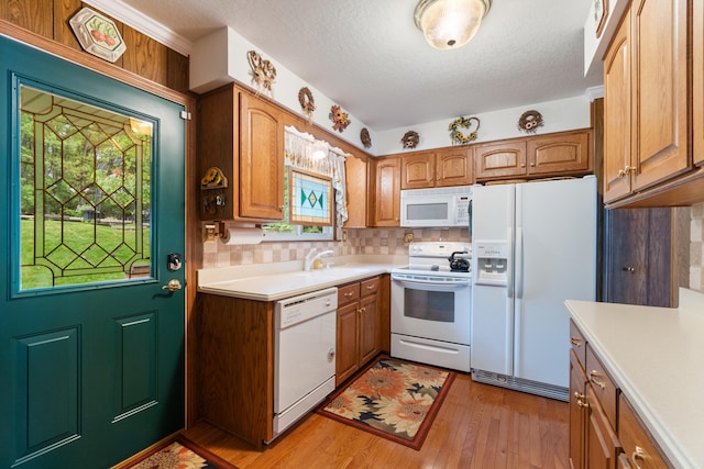 11676 Bradley Dr, Jerome, MI 49249 - kitchen with white appliances, light countertops, light wood-style flooring, decorative backsplash, and brown cabinetry