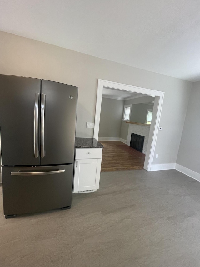 1007 Alto Ave SE, Grand Rapids, MI 49507 - kitchen featuring freestanding refrigerator, white cabinets, a tiled fireplace, baseboards, and dark stone countertops