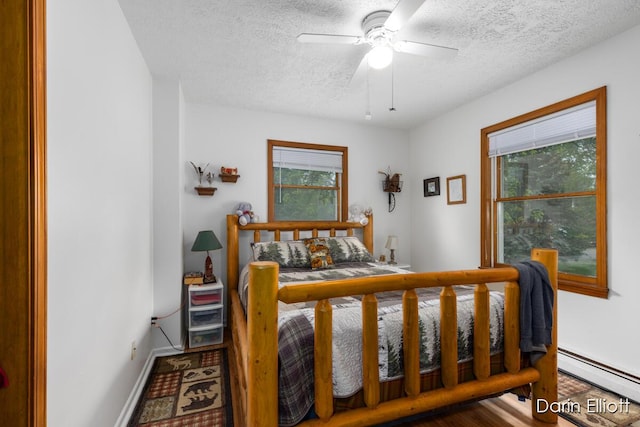 604/606 N New Dexter St, Ionia, MI 48846 - bedroom featuring a textured ceiling, baseboard heating, baseboards, and ceiling fan
