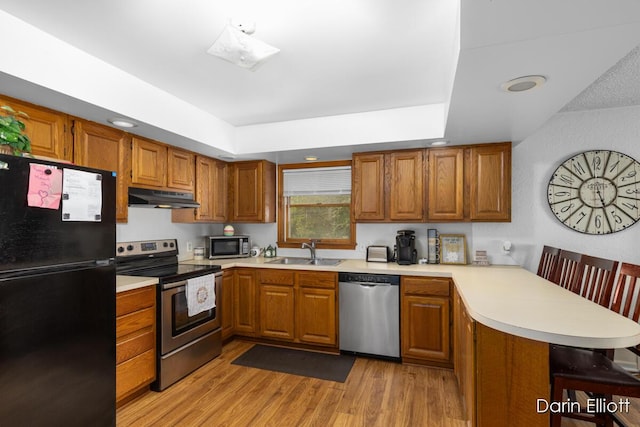 604/606 N New Dexter St, Ionia, MI 48846 - kitchen featuring stainless steel appliances, under cabinet range hood, a peninsula, a sink, and brown cabinetry